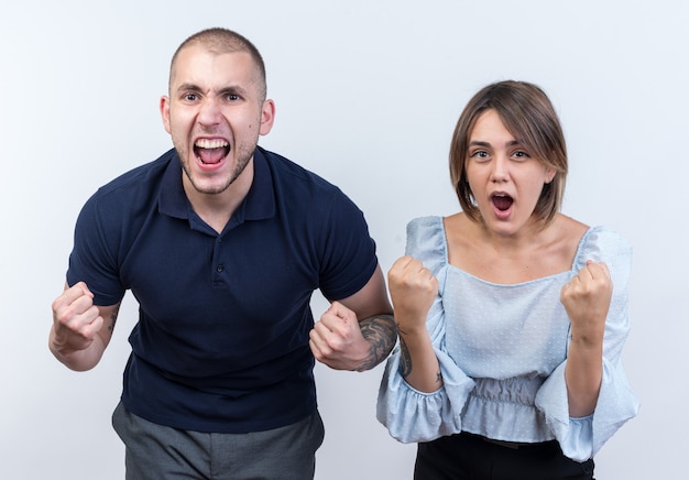 Foto grátis jovem casal lindo com roupas casuais homem e mulher cerrando os punhos, feliz e animado, olhando em pé