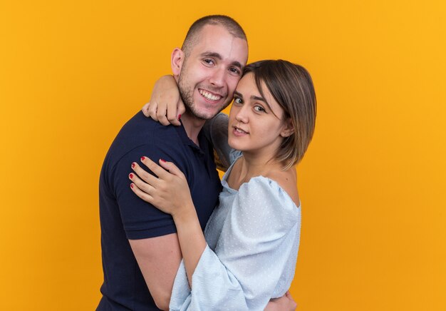 Jovem casal lindo com roupas casuais, homem e mulher se abraçando, feliz e sorrindo, olhando em pé