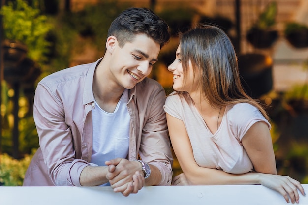 Jovem casal lindo conversando no terraço do restaurante com roupas casuais