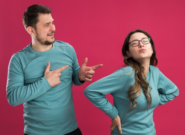 Jovem casal lindo em roupas casuais azuis, homem e mulher feliz no amor, se divertindo juntos, homem apontando para sua linda namorada