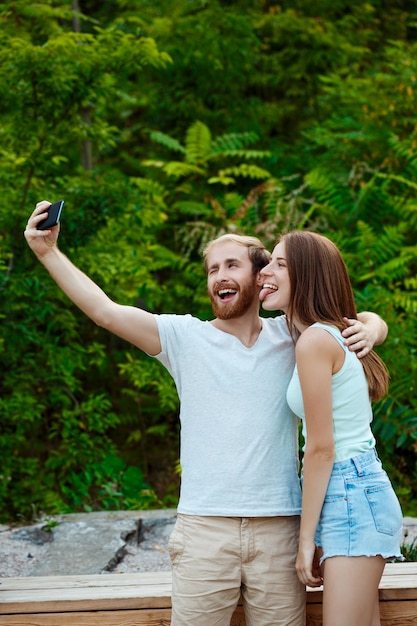 Jovem casal lindo fazendo selfie, sorrindo, caminhando no parque