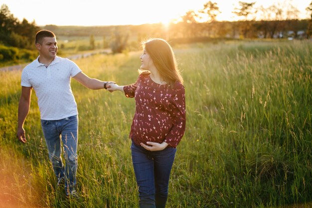 jovem casal lindo feliz no amor caminhando juntos na grama e árvores parque paisagem