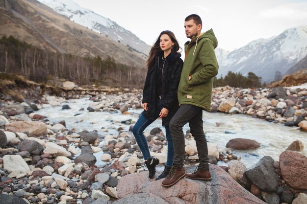 Jovem casal lindo hippie apaixonado, caminhando à beira do rio, natureza selvagem, férias de inverno