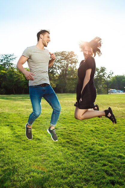 Jovem casal lindo pulando no parque.