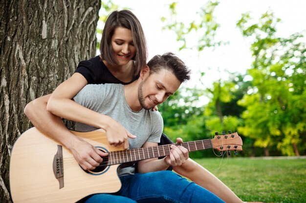 Jovem casal lindo sorrindo, descansando no piquenique no parque.