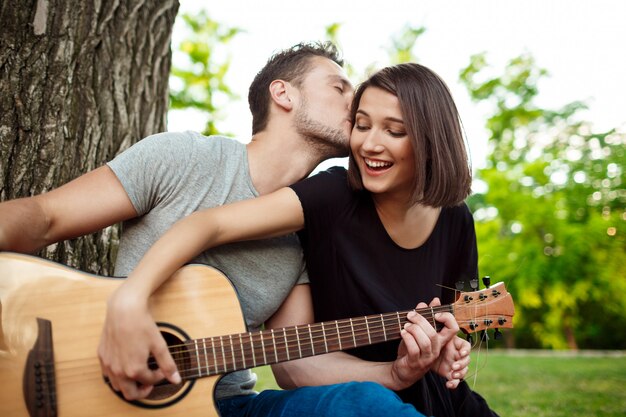 Jovem casal lindo sorrindo, descansando no piquenique no parque.