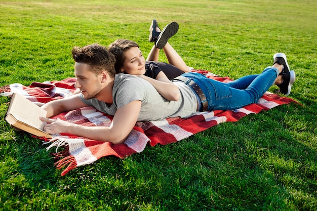 Jovem casal lindo sorrindo lendo no parque.