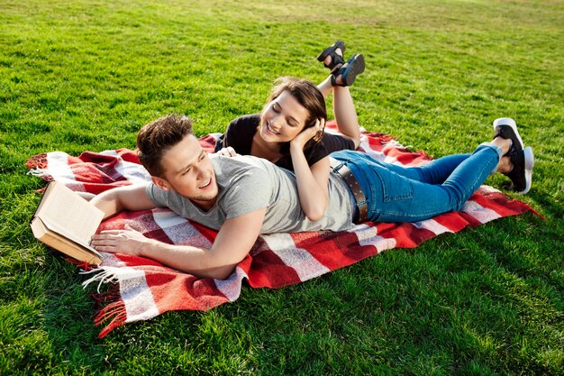 Jovem casal lindo sorrindo lendo no parque.