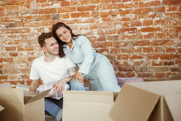 Jovem casal mudou-se para uma nova casa ou apartamento. Deitados juntos, acariciando, abraçando, se divertindo no dia da mudança