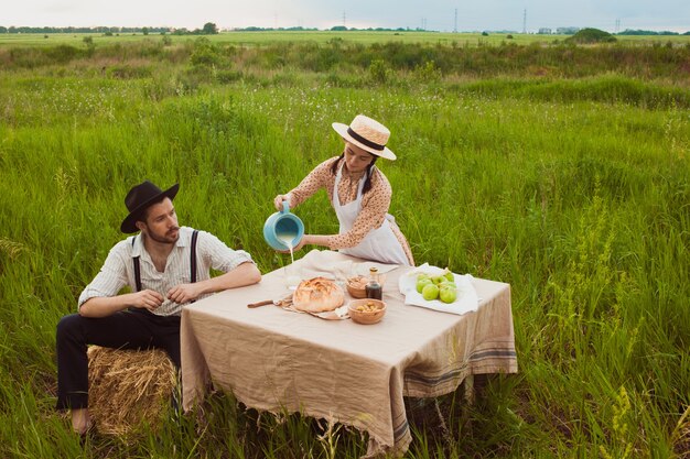 Jovem casal no campo, comendo e bebendo