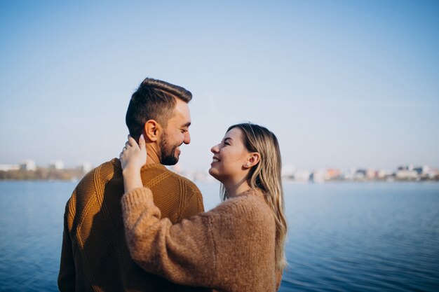 Jovem casal no parque em pé junto ao rio