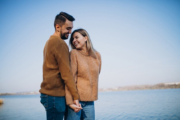 Jovem casal no parque em pé junto ao rio