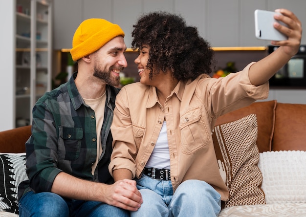 Foto grátis jovem casal olhando um ao outro e tirar uma selfie