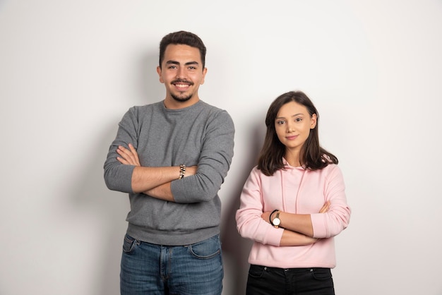 Jovem casal posando de braços cruzados em branco.