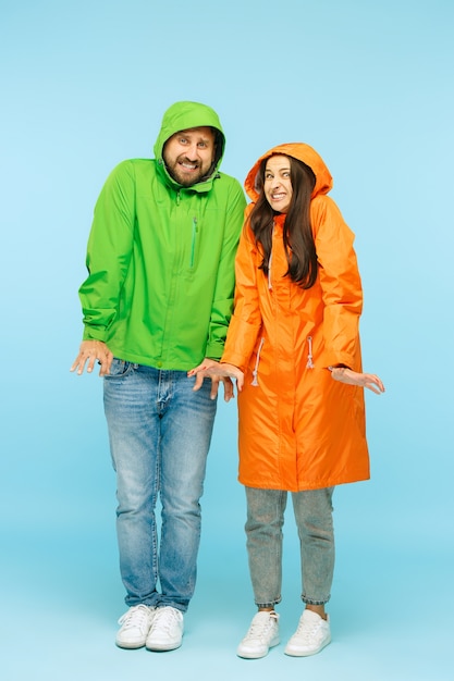 jovem casal posando no estúdio outono casaco isolado em azul. Emoções negativas humanas. Conceito de clima frio. Conceitos de moda feminina e masculina