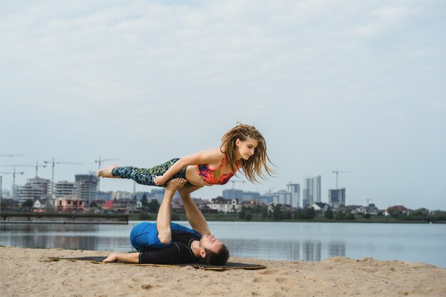 jovem casal praticando yoga no fundo da cidade