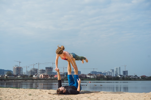 jovem casal praticando yoga no fundo da cidade