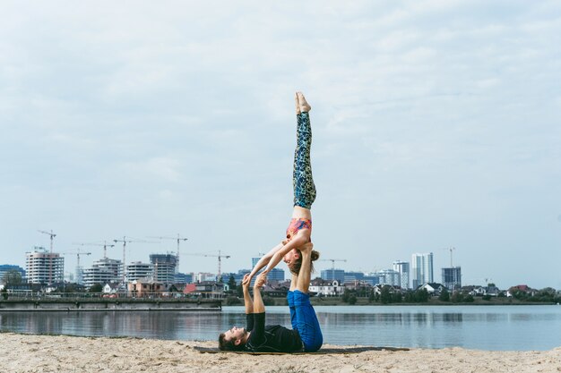 jovem casal praticando yoga no fundo da cidade