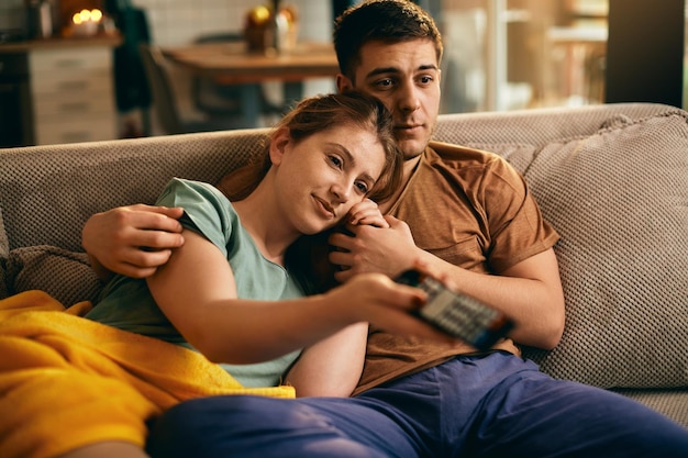 Jovem casal relaxado assistindo TV em casa