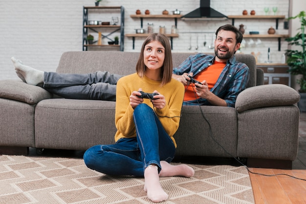 Jovem casal relaxando em casa jogando o videogame em casa a sorrir