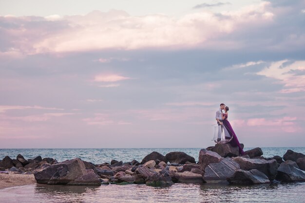 Jovem casal romântico relaxante na praia, assistindo o pôr do sol