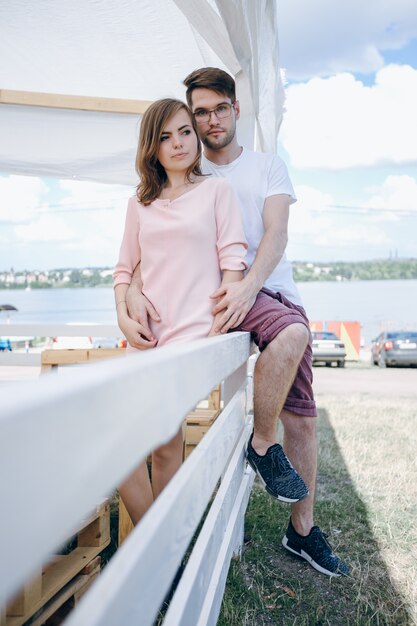 Jovem casal se abraçando e sentada sobre uma cerca branca