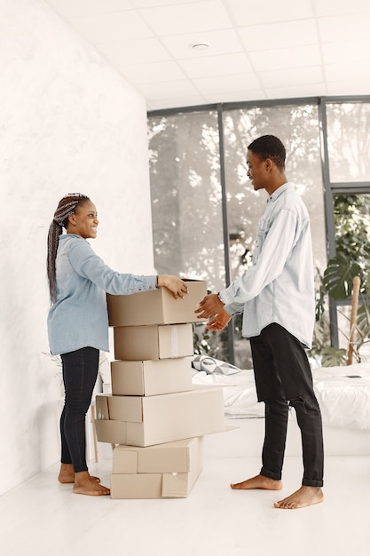 Jovem casal se mudando para a nova casa juntos. Casal afro-americano com caixas de papelão.