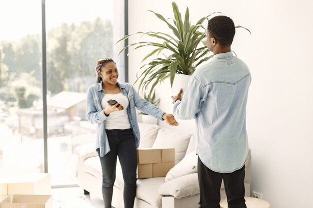 Jovem casal se mudando para a nova casa juntos. Casal afro-americano com caixas de papelão.