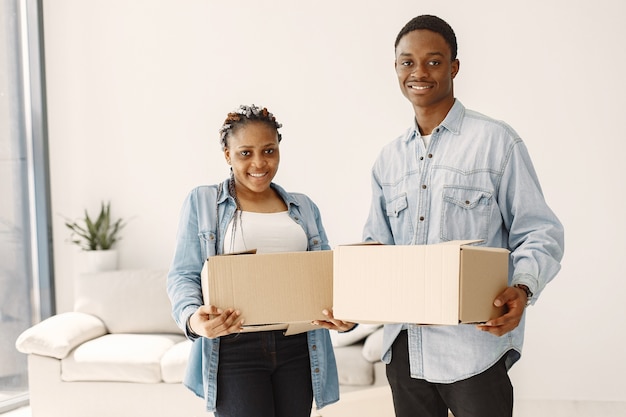 Jovem casal se mudando para a nova casa juntos. Casal afro-americano com caixas de papelão.