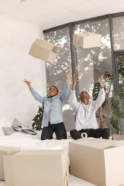 Foto grátis jovem casal se mudando para a nova casa juntos. casal afro-americano com caixas de papelão.