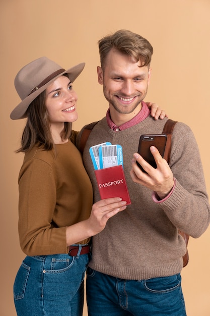 Jovem casal segurando smartphone e passagens aéreas para viajar