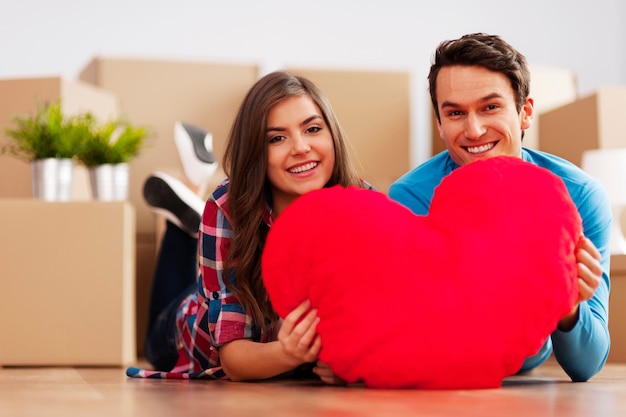 Jovem casal segurando um formato de coração em seu novo apartamento