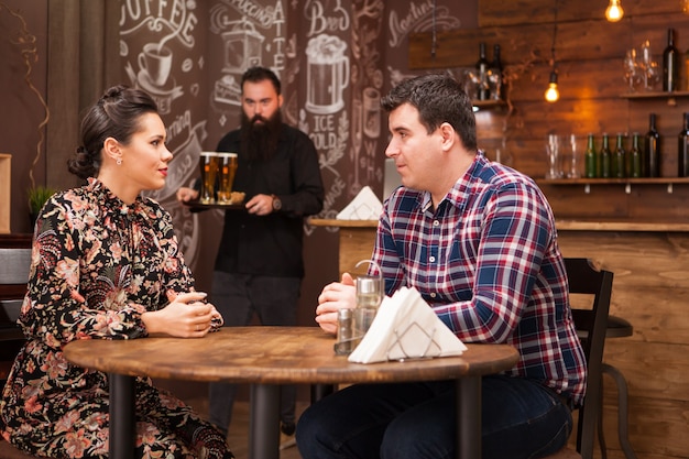 Jovem casal sentado em um restaurante conversando e se divertindo.