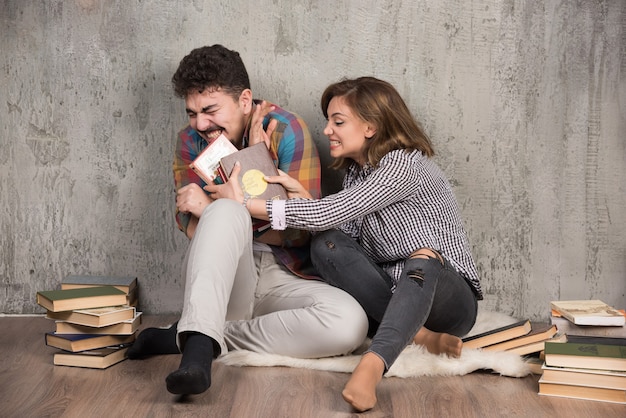 jovem casal sentado no chão com livros