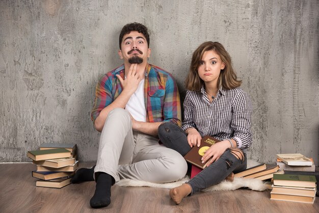 jovem casal sentado no chão com livros