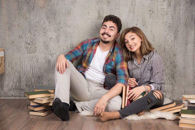 jovem casal sentado no chão com livros