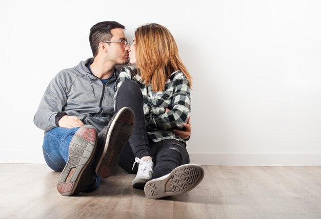 Jovem casal sentado no chão se beijando