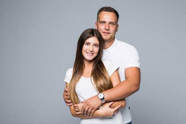 Jovem casal sorridente estudante estúdio isolado camiseta branca jeans afago