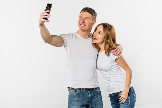 Foto grátis jovem casal tendo selfie no telemóvel isolado no fundo branco