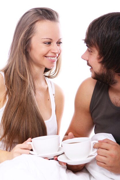 Jovem casal tomando café na cama