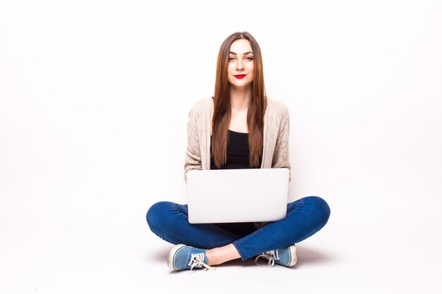 Jovem casual sentada sorrindo segurando um laptop