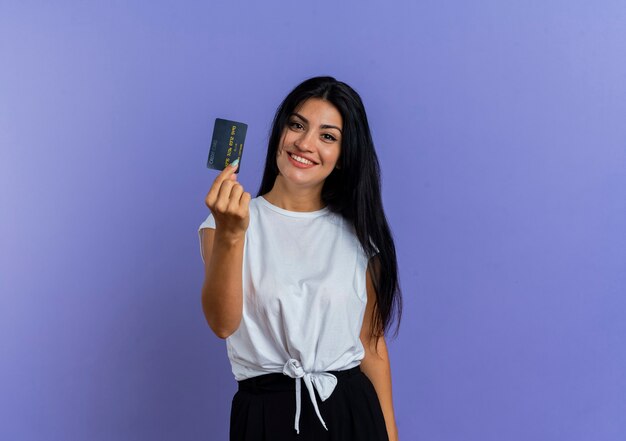 Jovem caucasiana sorridente segurando um cartão de crédito