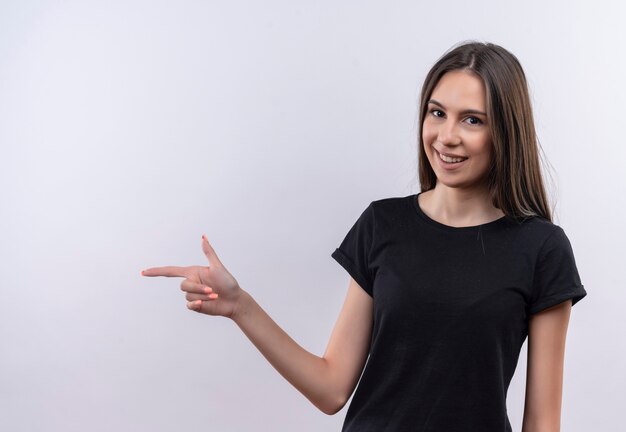 jovem caucasiana vestindo uma camiseta preta apontando para o lado na parede branca isolada