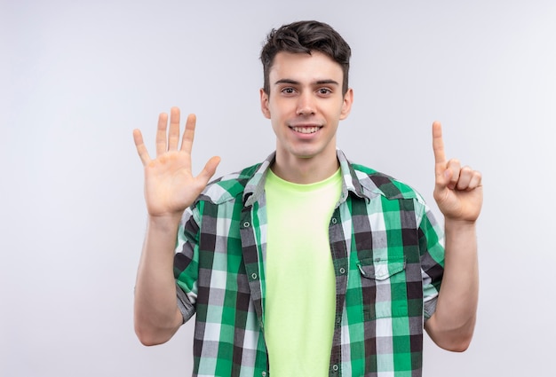 Jovem caucasiano sorridente com camisa verde mostrando cinco e um com as mãos no fundo branco isolado