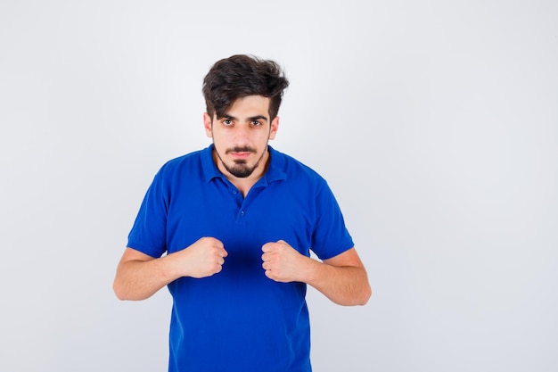 Jovem cerrando os punhos em uma camiseta azul e parecendo sério