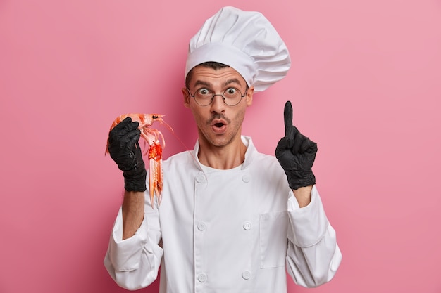 Jovem chef bonito segurando lagostins crus isolados