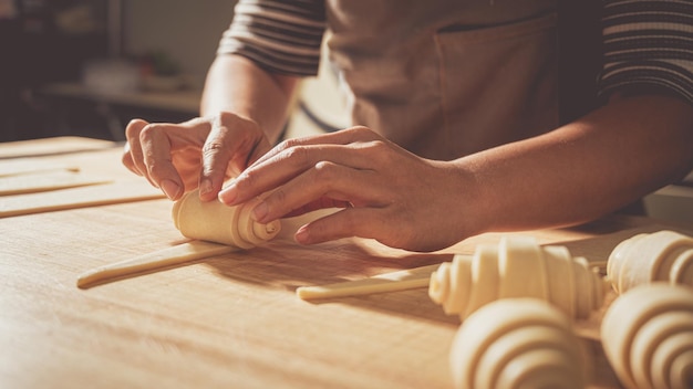 Jovem chef de pastelaria fazendo um croissant no conceito de padaria e fundo de padaria