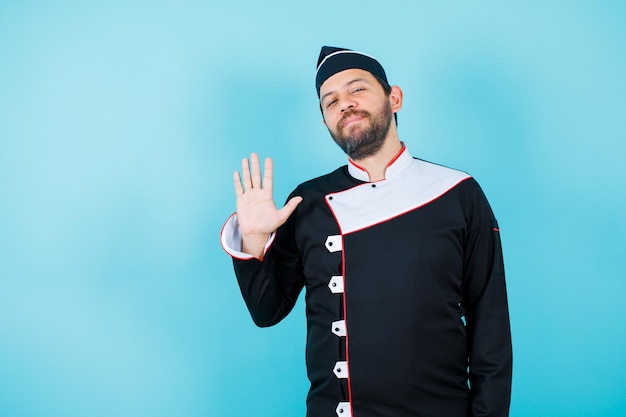 Jovem chef está mostrando cinco gestos sobre fundo azul