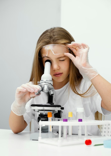 Jovem cientista intrigada usando microscópio