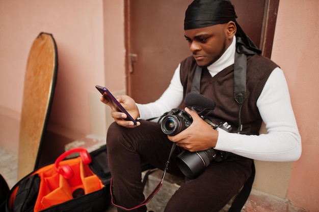 Foto grátis jovem cinegrafista americano africano profissional segurando câmera profissional com equipamento profissional afro cameraman vestindo duraq preto fazendo vídeos